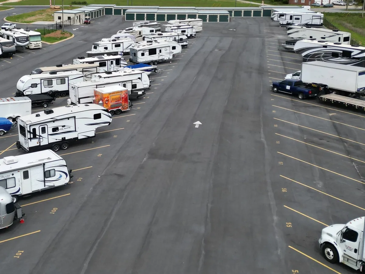 Wide paved RV storage lot with numbered spaces up to 70 feet long